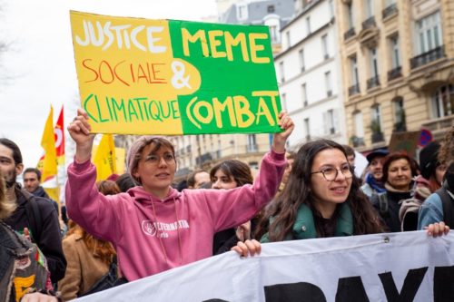 Une militante du collectif PJC – Alliance écologique et sociale tient une pancarte « Justice sociale & climatique même combat »