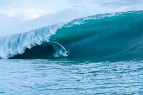 Un surfeur surfe une énorme vague sur la plage de Teahupoo en Polynésie française