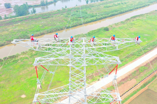 Des ouvriers installent des accessoires à une hauteur de plus de 70 mètres sur le chantier de construction d'un projet de transmission externe de 220 kilovolts pour une centrale électrique de pointe au gaz en Chine. Crédit CFOTO/Sipa USA/SIPA